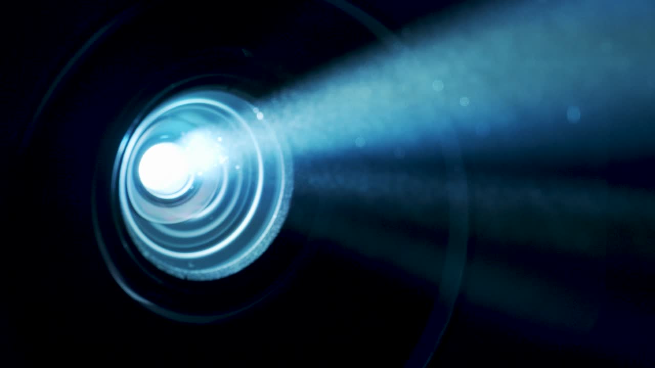 Close up of video projector lens shining through smoke