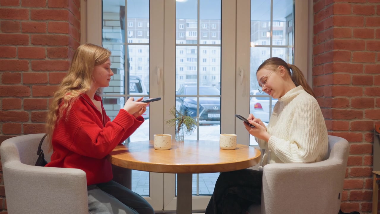 Bir Kafe Masasında Telefonlarına Dalmış Genç Kadınlar