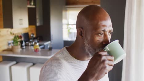 Senior-african-american-man-spending-time-in-log-cabin-and-drinking-coffee,-slow-motion