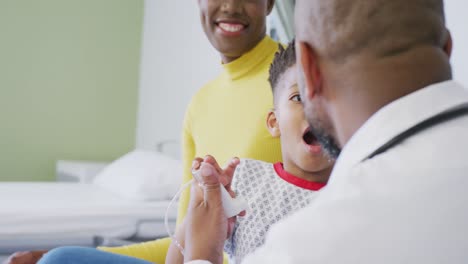 Médico-Varón-Afroamericano-Examinando-A-Un-Paciente-Infantil-En-El-Hospital