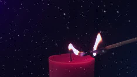 animation of snowflakes falling over match lighting red candle on black background