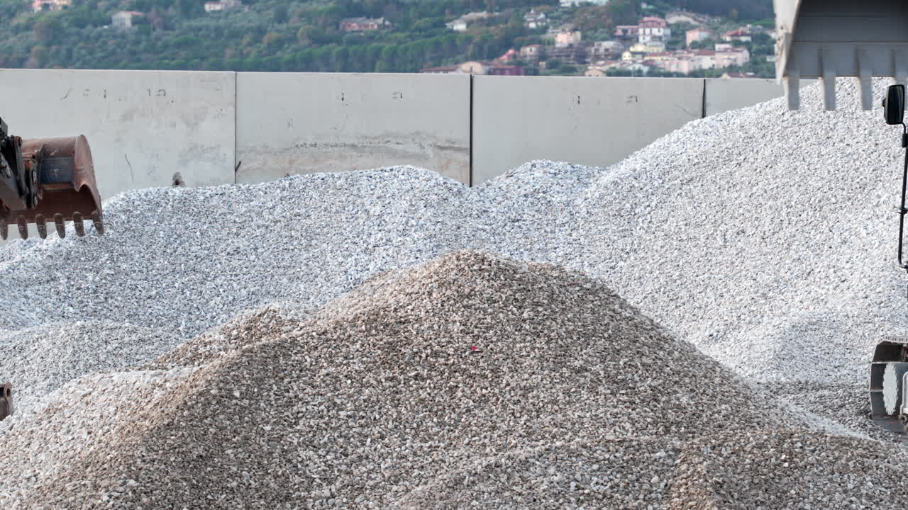 Excavator moving gravel at construction site, displaying industry work