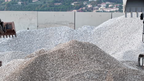 excavator moving gravel at construction site, displaying industry work