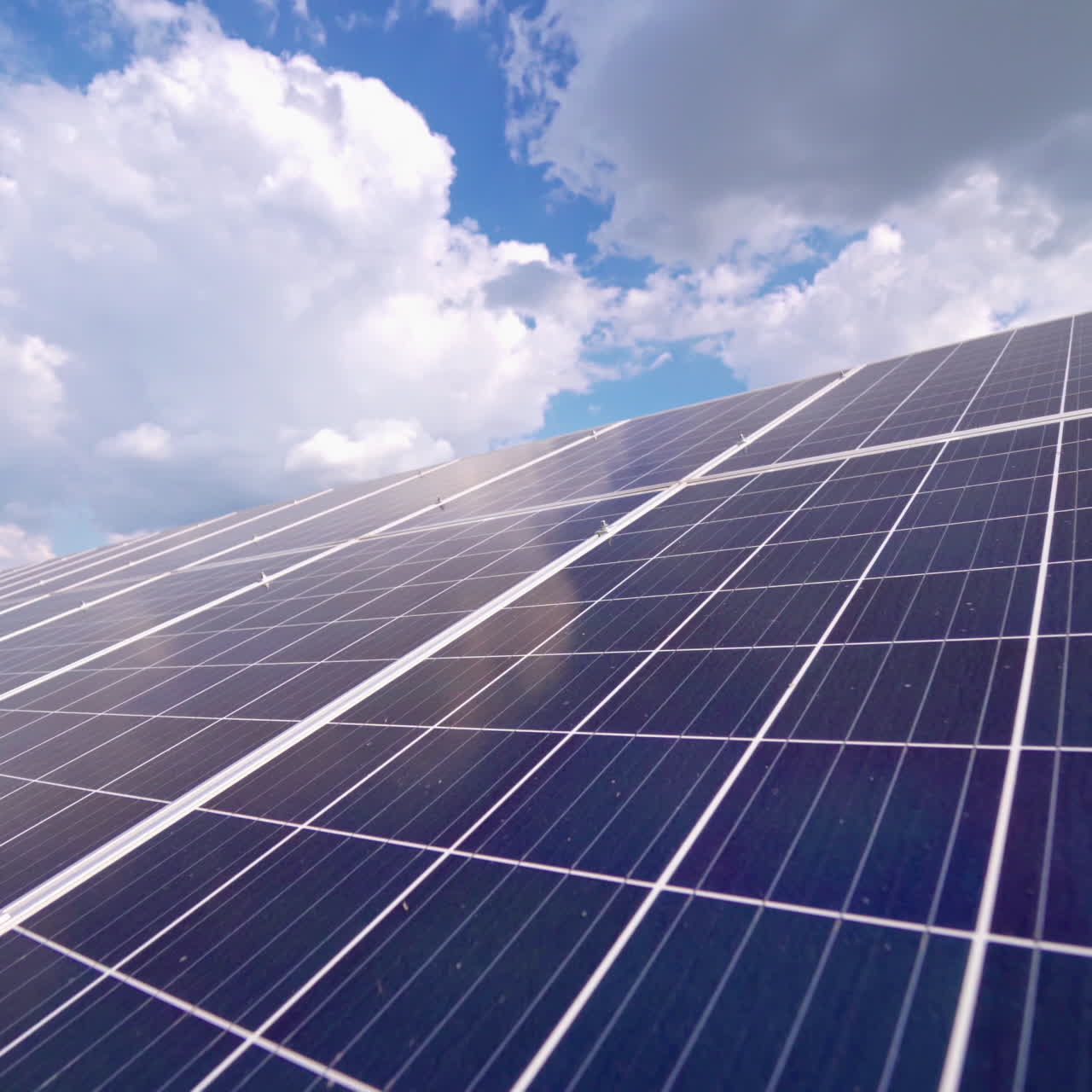 Close-up of solar panel at sunlight. Alternative source of energy. Innovative solar cell panel under blue sky with white clouds.