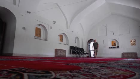 hombre caucásico descalzo entra respetuosamente en la mezquita azul en yerevan, brazo