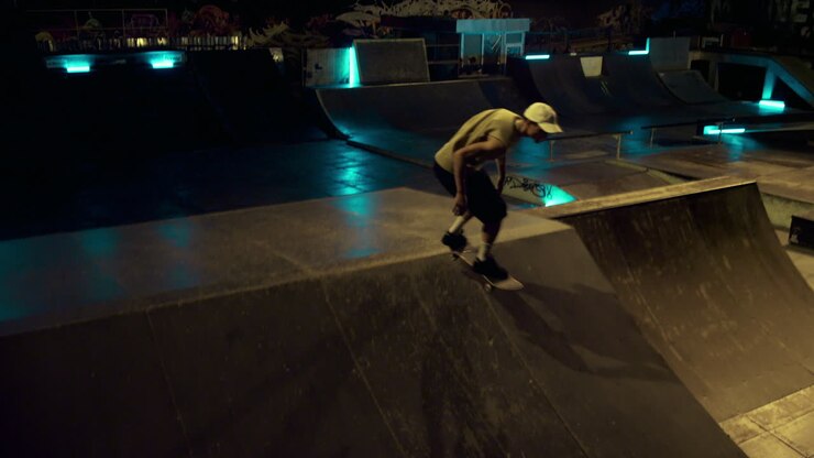 Atleta sportivo che si prepara per una competizione di skateboard su rampa in uno skatepark notturno.