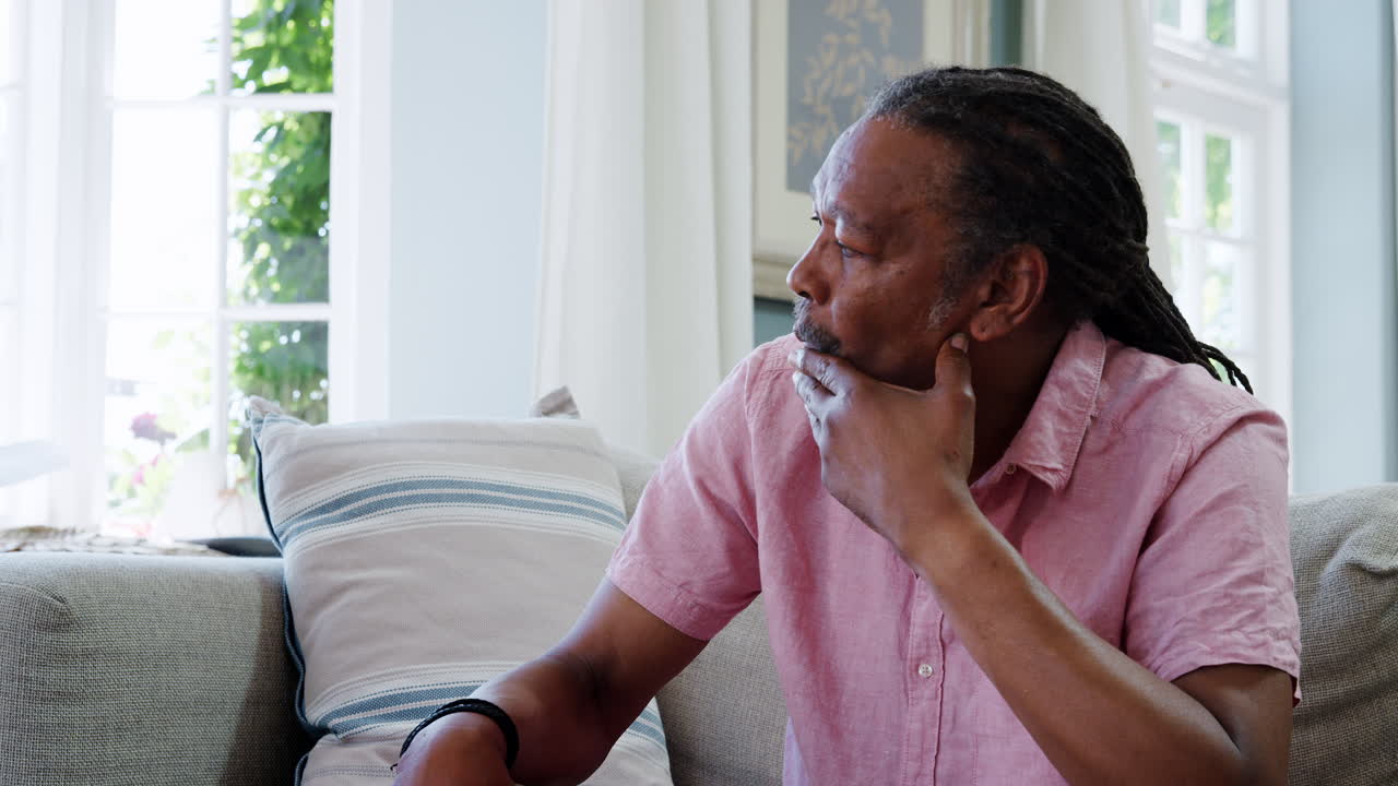 hombre mayor sentado en el sofá en casa sufriendo de depresión