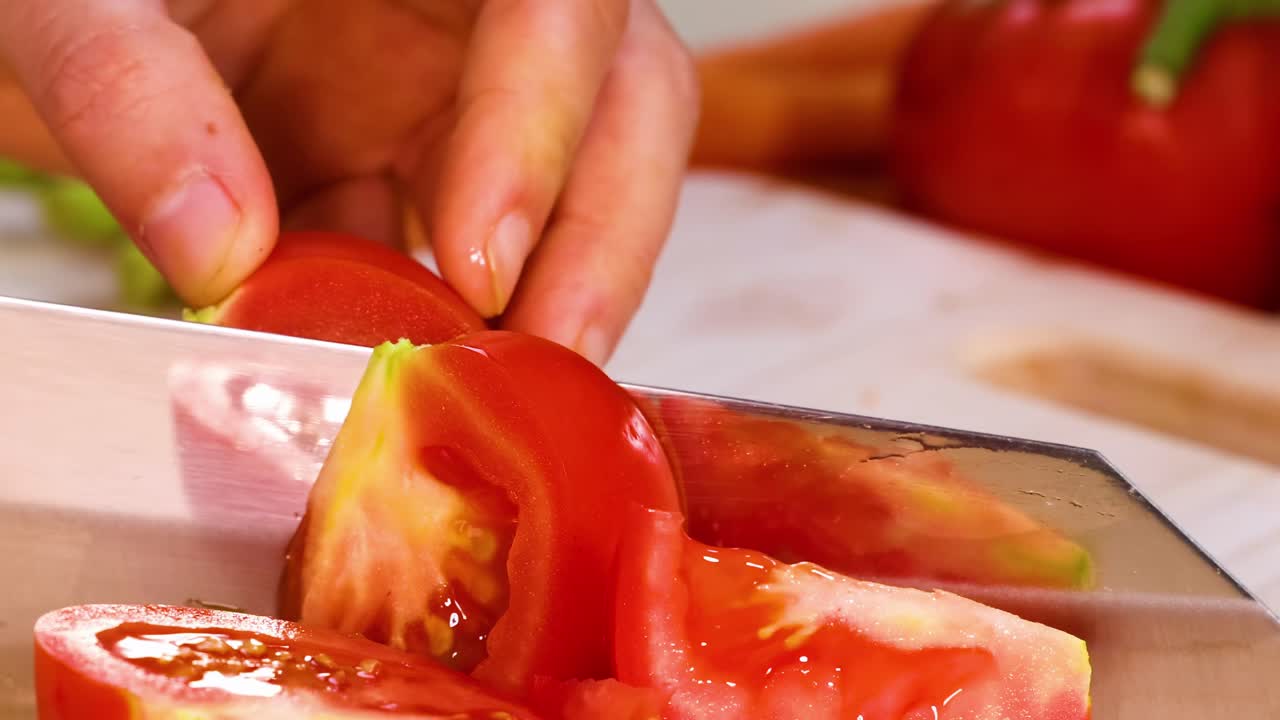 Close-up view of hands skillfully slicing ripe tomatoes with a sharp knife on a wooden surface.