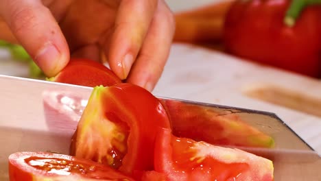 close-up view of hands skillfully slicing ripe tomatoes with a sharp knife on a wooden surface.