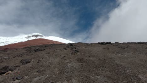 a panoramic establishing tilt upward of cotopaxi volcano, ecuador, showcasing volcanic slopes and dramatic mist