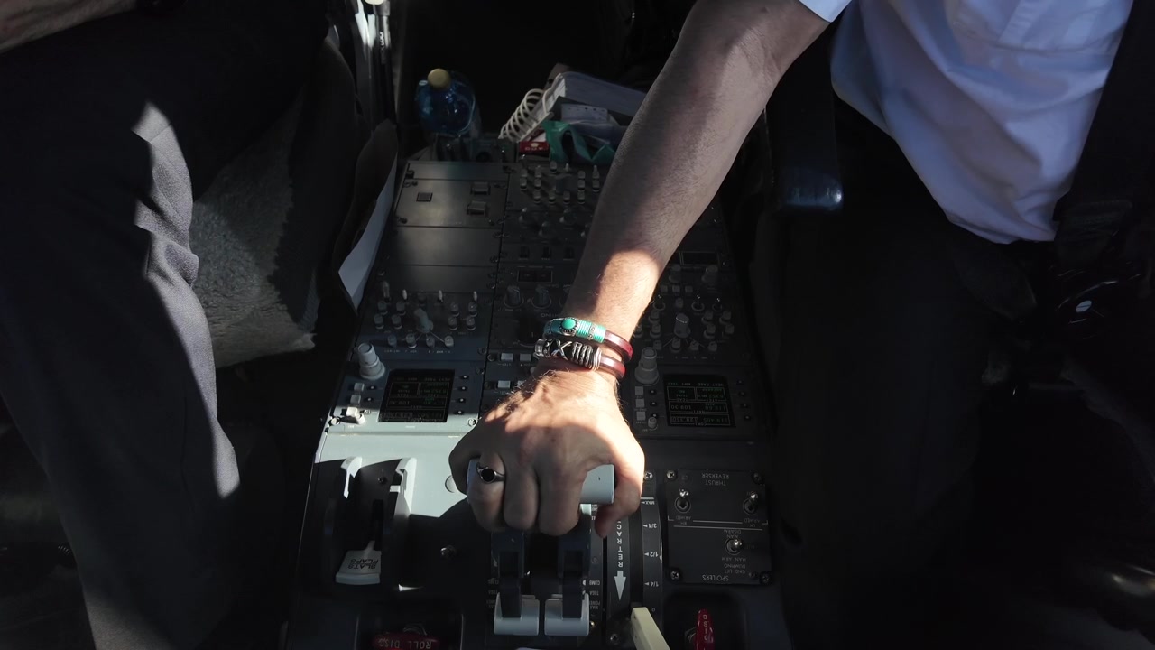 Hand of a caucasian pilot, Captain seat, adjusting the engines thrust levers inside a jet cockpit with the sunlight bathing the scene. 4K 60FPS