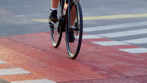Man-legs-pedaling-city-crosswalk-red-cycling-path-closeup.-Urban-traveler-riding