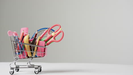 acercamiento de materiales escolares de carrito de compras en miniatura y espacio de copia en fondo gris