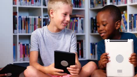niños de la escuela usando tableta digital en la biblioteca