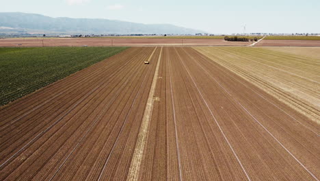 Slow-Motion-wide-drone-HIGH-ANGLE-of-artichoke-farm-field-and-weeding-machine-moving-forwards