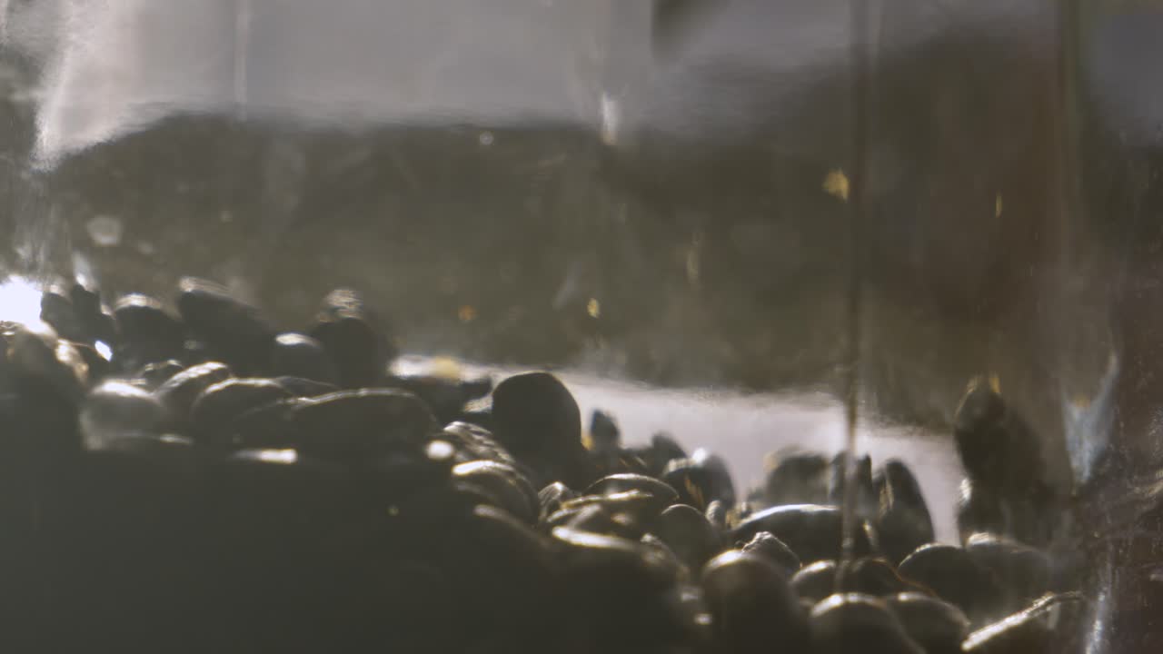 Roasted Coffee Beans Being Dropped into Glass Jar in Bright Sunlight. Ready to Grind and Make into Caffeine Hot Drink Beverage 4K.