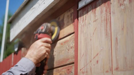 Alte-Farbe-Vom-Holzhaus-Durch-Schleifmaschine-Entfernen