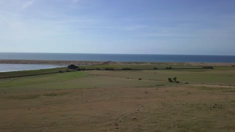 seguimiento aéreo y rotación de derecha a izquierda mirando a través de la laguna de la flota y la playa de chesil, dorset, inglaterra