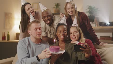 grupo de amigos en la fiesta de cumpleaños sosteniendo un pastel con velas