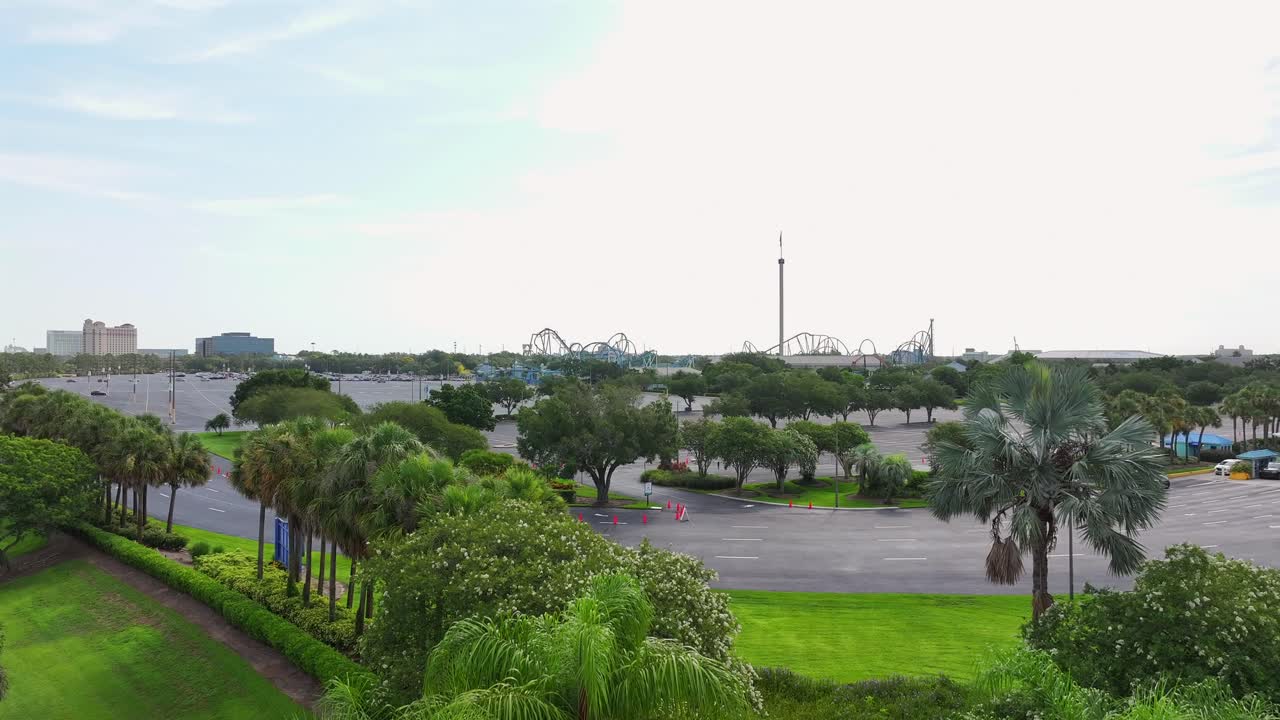SeaWorld entrance sign surrounded by greenery and palm trees in Orlando, Florida. The iconic logo is displayed on a rocky structure with mist effects. Aerial.
