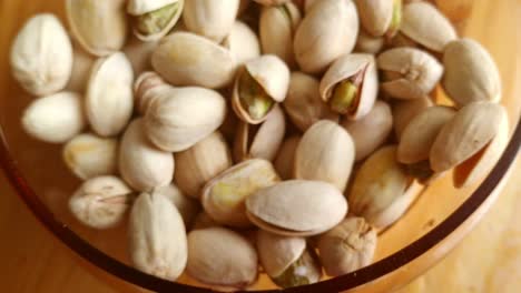 glass bowl full of pistachio seeds on kitchen table from above, dolly