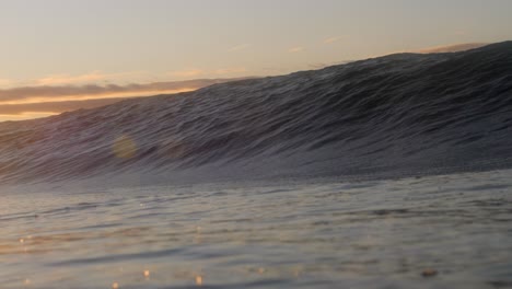 the golden glow of the rising sun as a short, heavy wave crashes