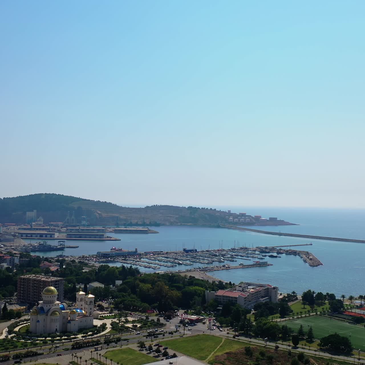 Modern resort city at the shore of Adriatic Sea. Drone footage above the cityscape and waterscape. Bar, Montenegro from aerial view