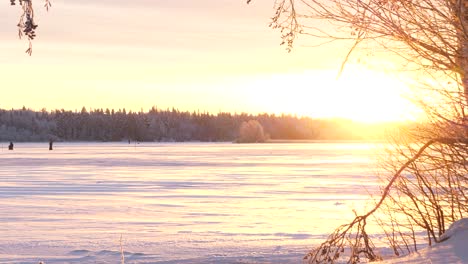 winter solstice, orange and purple colors on winter landscape as sun rises for a few hours, frozen lake in lapland