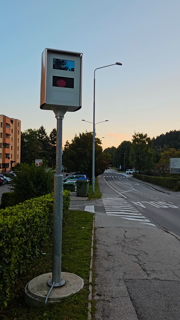 Speed camera watches a school zone by crosswalk and limit sign; static vertical shot at dusk