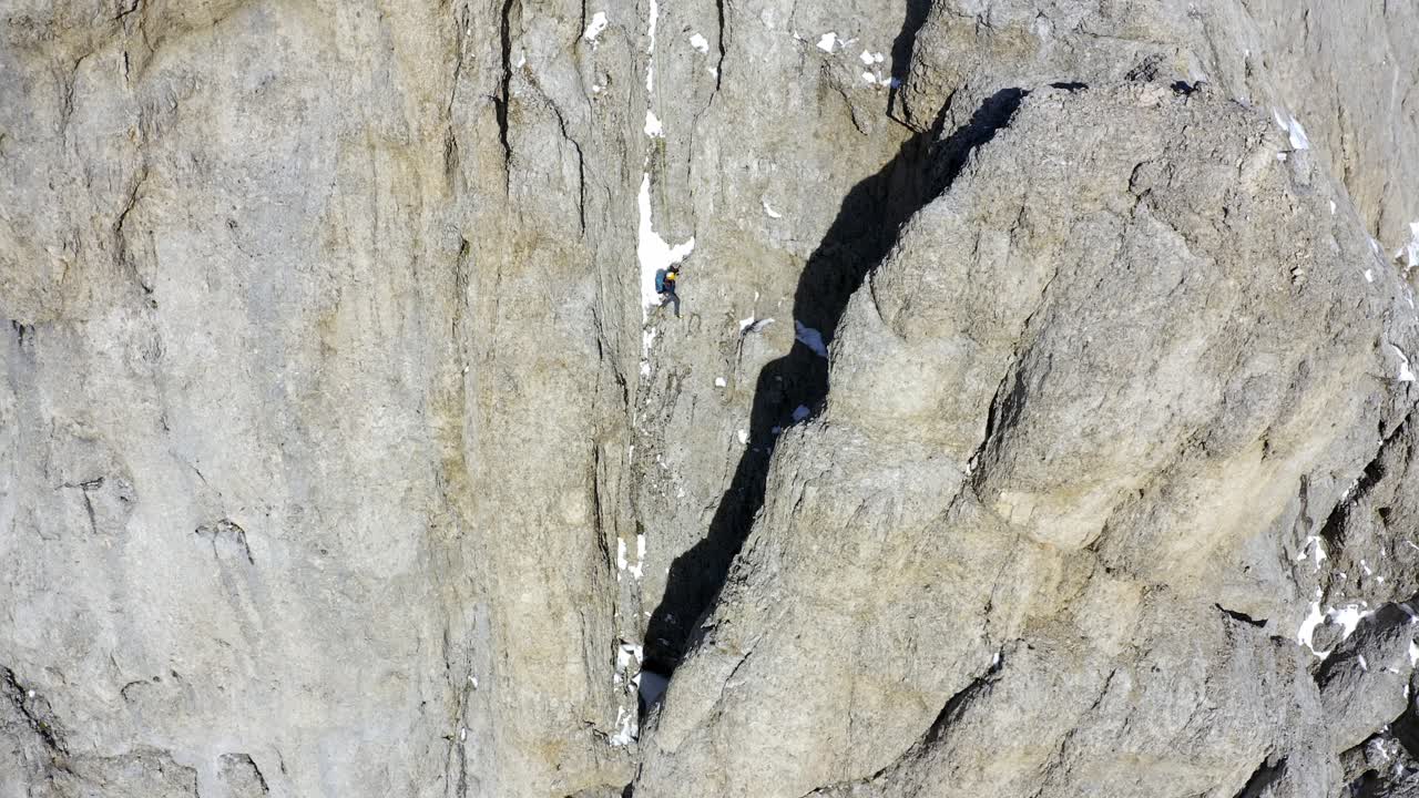 toma aérea inclinada hacia arriba que muestra a un excursionista extremo escalando en la escarpa de la montaña marmolada durante la luz del sol