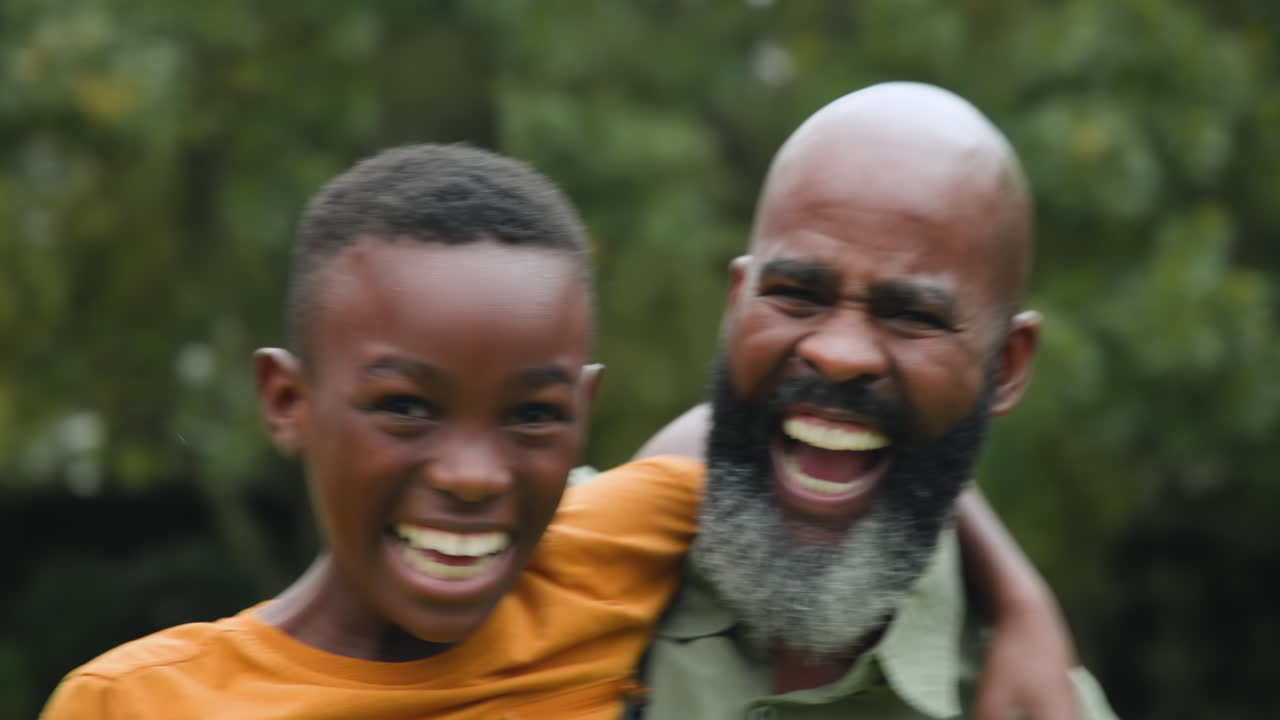 Padre e figlio che ridono gioiosamente all'aperto, abbracciando insieme la felicità familiare.