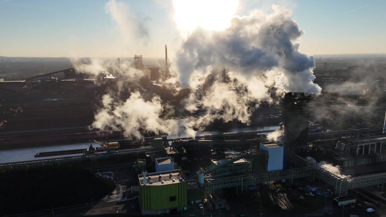 Backlit drone retreat reveals layered smoke harbor and silhouetted factory structures in dramatic sunrise
