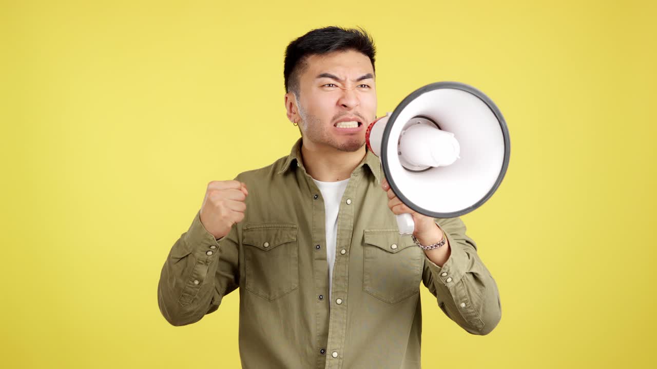Angry Asian man shouting into a megaphone with a raised fist