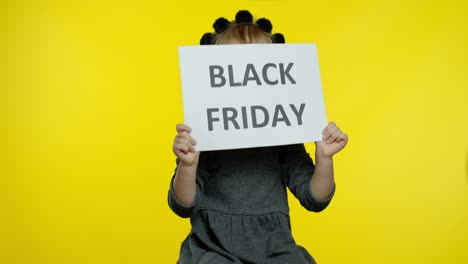 child girl showing black friday inscription, smiling, looking satisfied with low prices, discounts