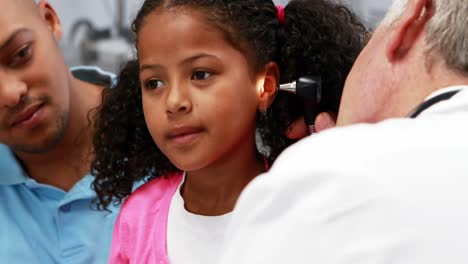 Male doctor examining patients ear with otoscope