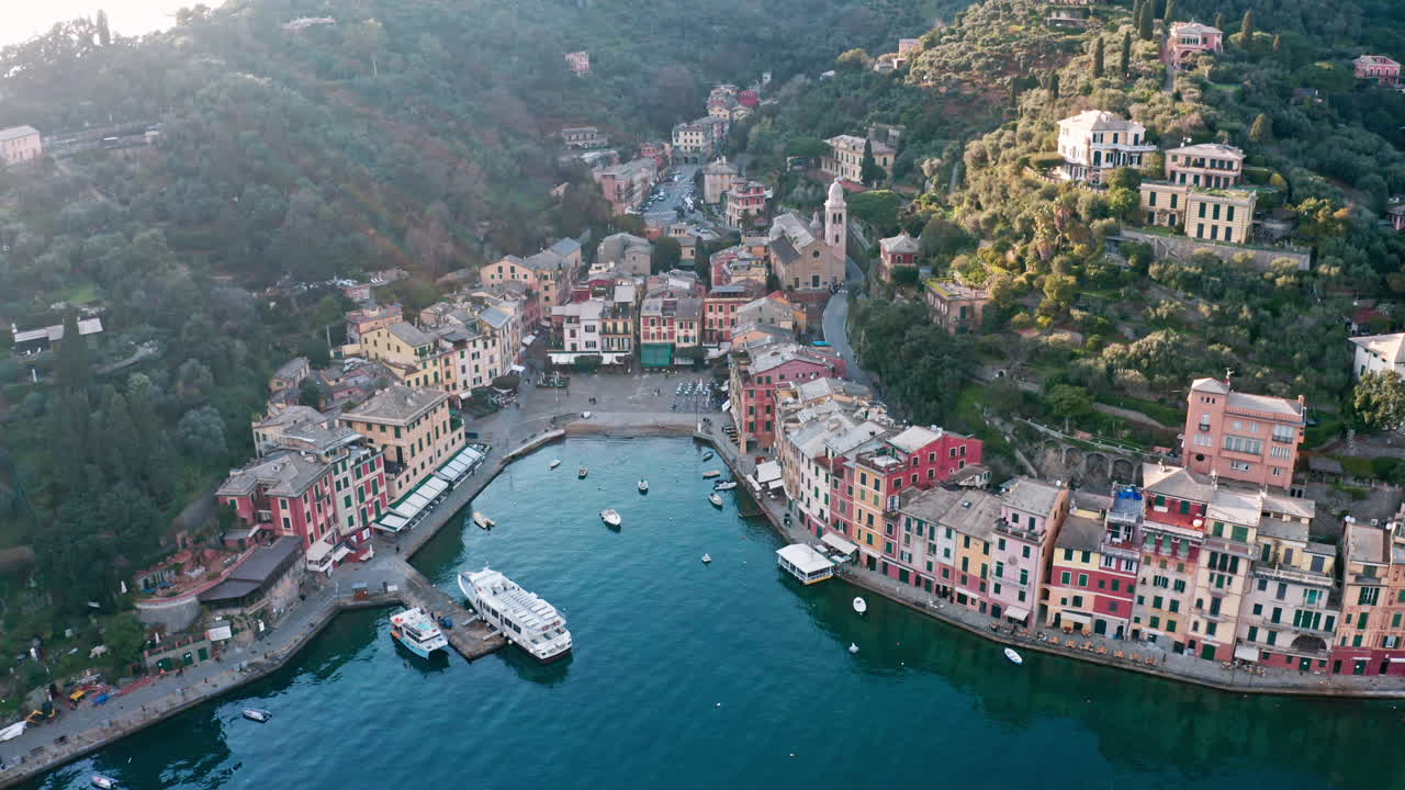 파스텔 색의 집들이 리구리아 해안의 작은 항구인 포르토피노를 둘러싸고 있습니다.