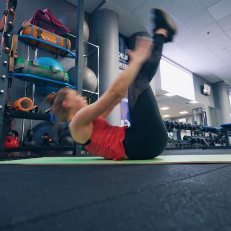 fit girl does exercises on mat in sports room. young woman stretching and bending her slim body on the floor in modern fitness center.