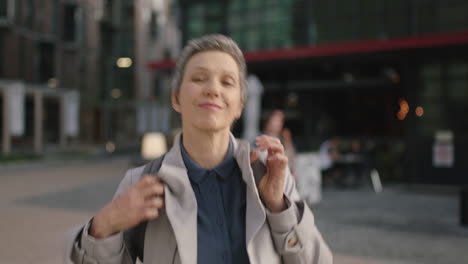 portrait-of-mature-business-woman-wearing-backpack-getting-ready-smiling-happy-enjoying-urban-travel-commuting