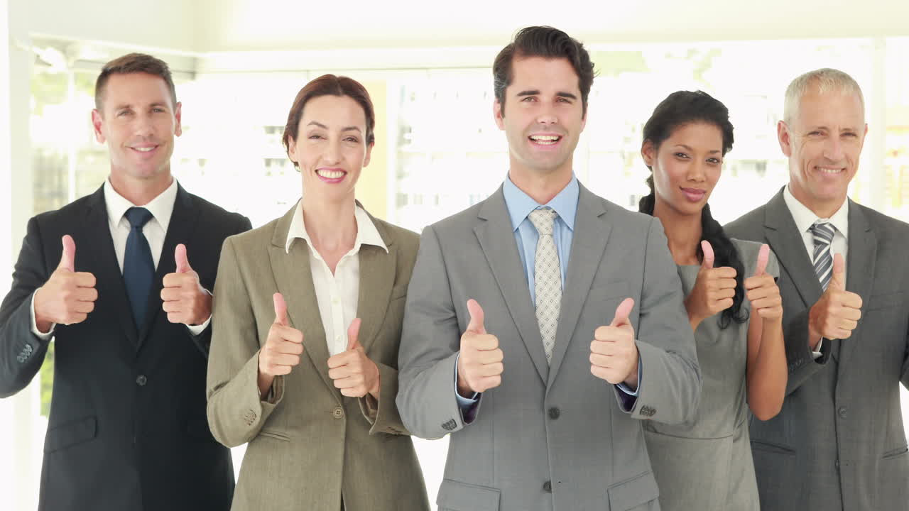Smiling business people looking at camera gesturing thumbs up