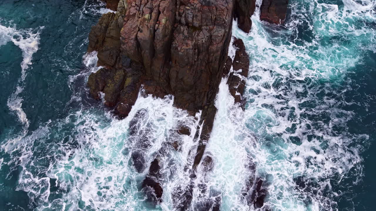 Onde vivaci che si infrangono sulle rocce frastagliate sulla costa durante una giornata luminosa in acque costiere