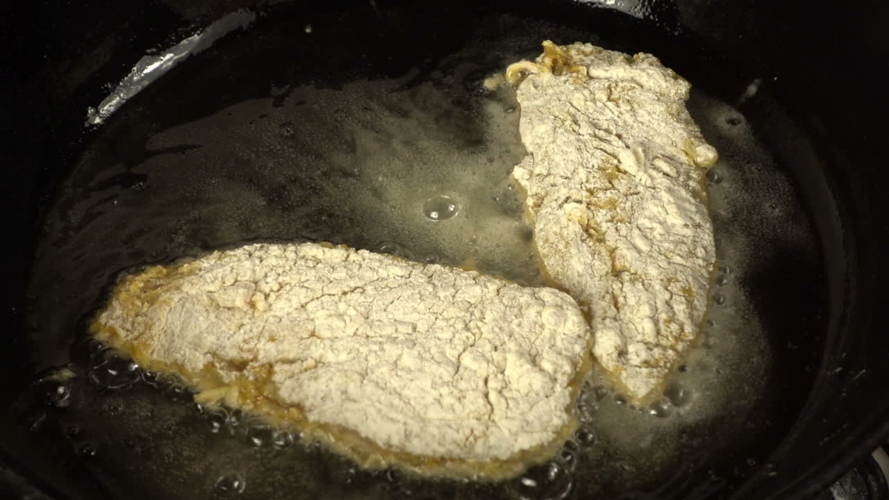 Zubereitung eines Hähnchenkoteletts in einer gusseisernen Pfanne. Zeitlupe. Kochvorgang