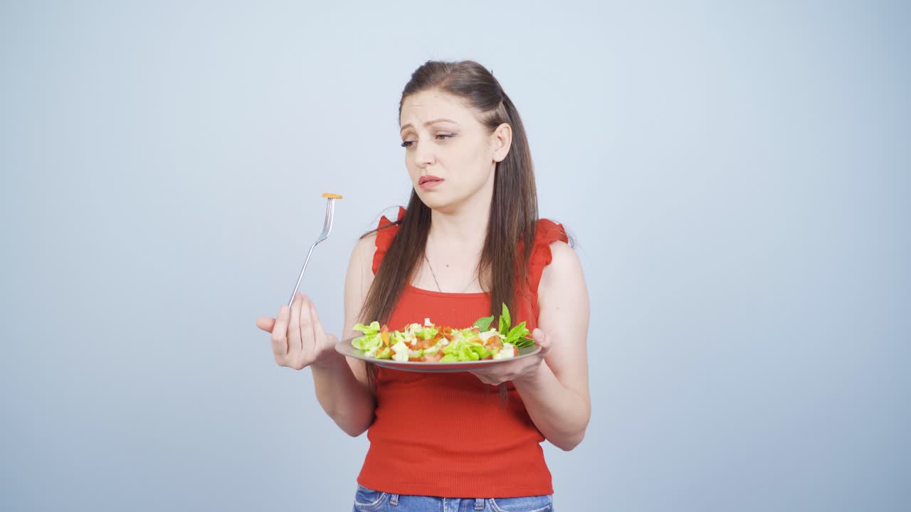 불행한 표정으로 포크에 있는 채소를 보는 사람. 다이어트에 어려움이 있습니다.