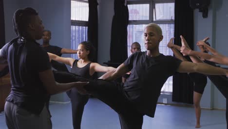 Mixed-race-fit-male-modern-dancer-stretching-up-during-dance-class-