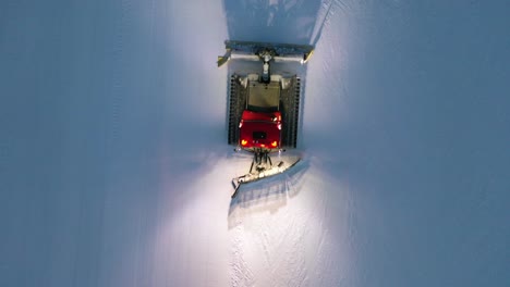 snow grooming - pistenbully snow groomer plowing snow at nassfeld-pressegger ski resort in austria - aerial top-down