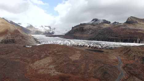 Wide-Aerial-Shot-of-a-Dirt-Road-Leading-Up-to-a-Glacier