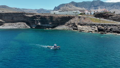 monitoreo aéreo de un barco de pesca que cruza las aguas turquesas del puerto de agaete en un día soleado