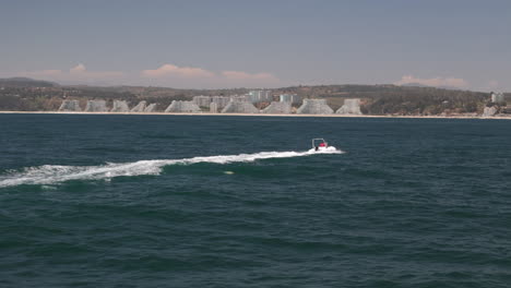 pan follow shot of motorboat speed by on the ocean waves
