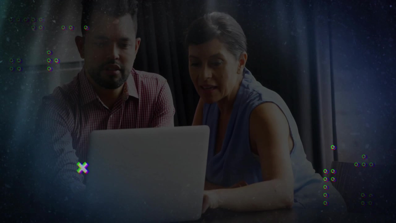 Woman and man reviewing laptop content in technology office, with glitch overlays and light streaks