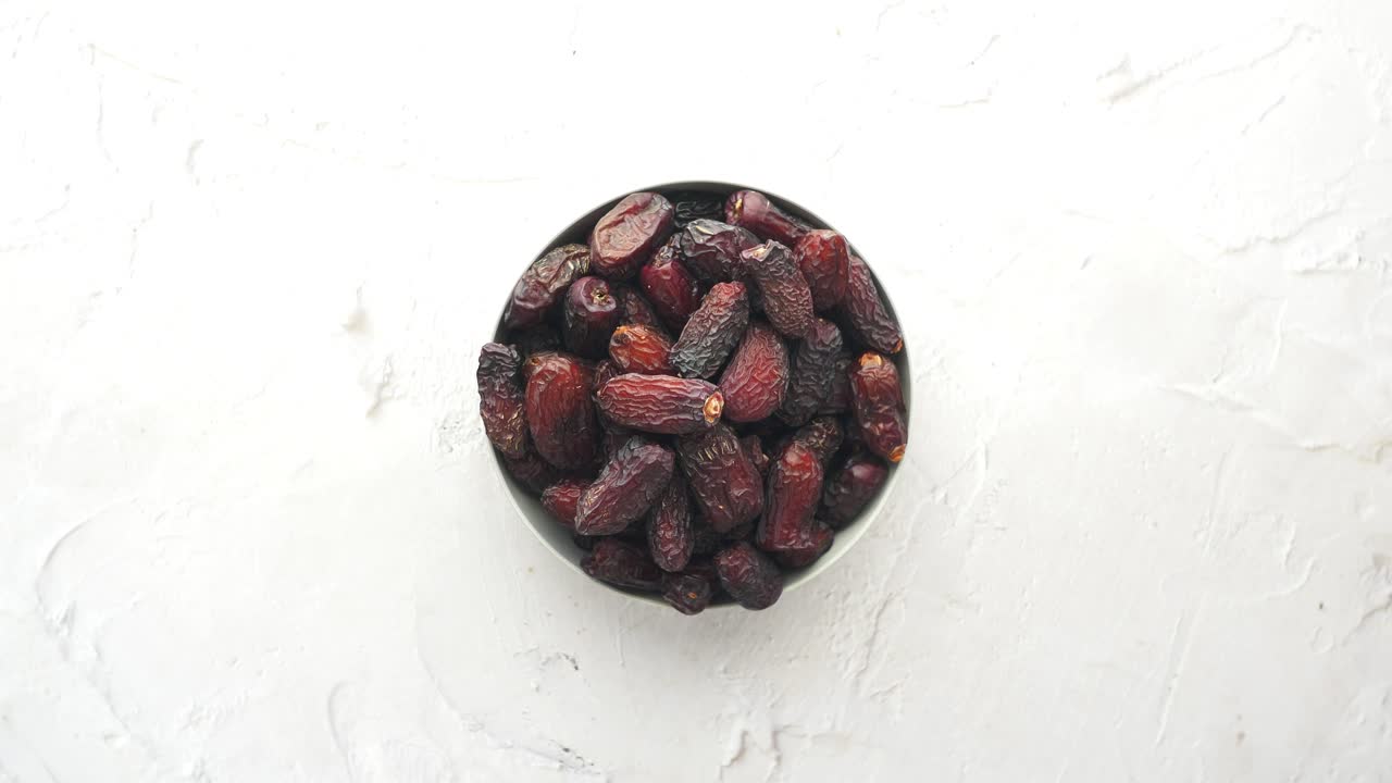 The concept of ramadan, hand pick date fruit from a bowl