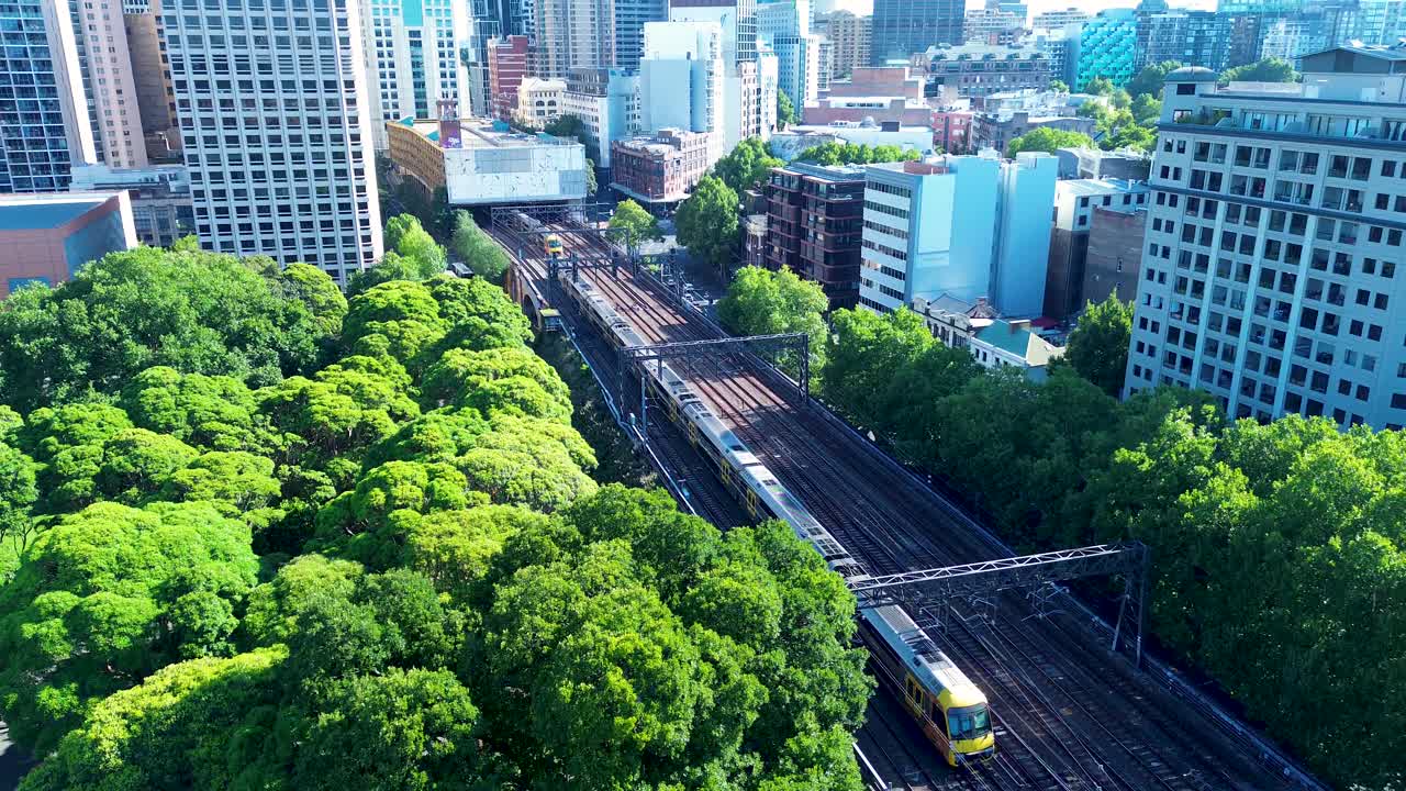 Drone aerial landscape of train on Sydney's Central station railway line tracks platform with trees in park Surry Hills CBD urban city metro buildings business